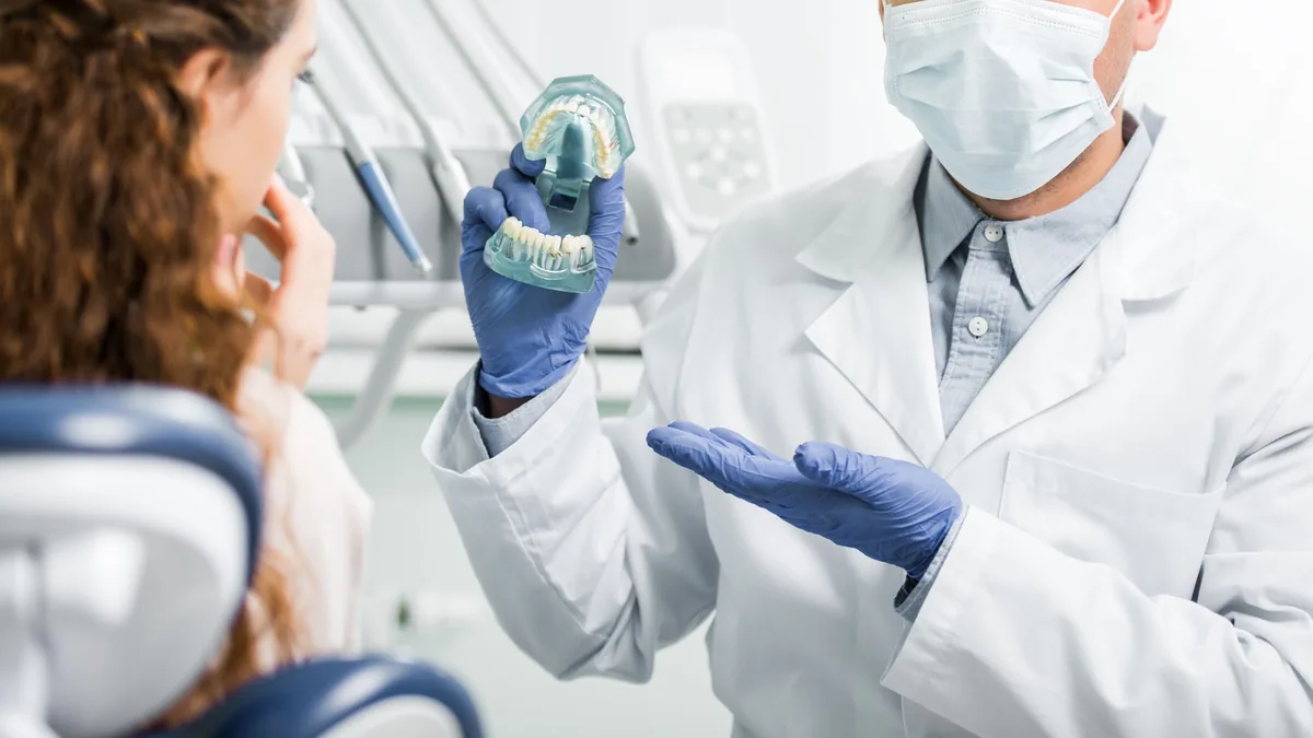 A clinician explaining treatment to a patient with a model of the jaw