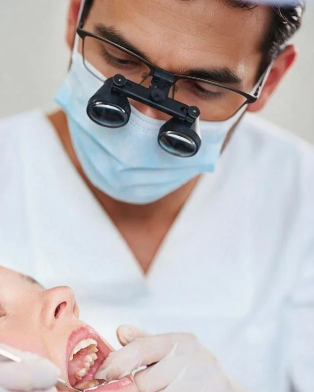 A dentist in surgical loupes treating a patient
