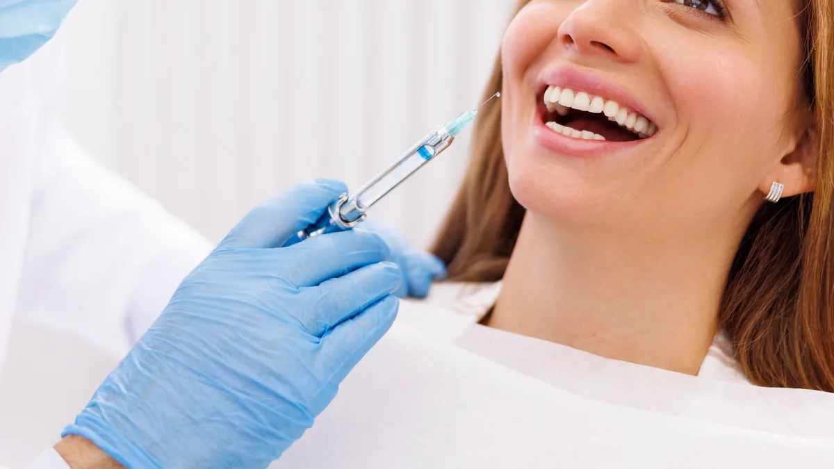 A gloved clinician preparing an injection beside a smiling patient
