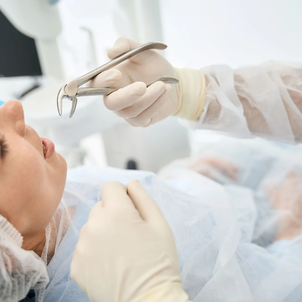Extraction forceps held ready above a patient in the chair